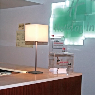 Receção com candeeiro, computador e letreiro Holiday Inn em parede branca