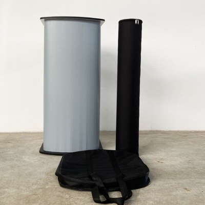 Expositor portátil cinza meia-lua com bolsa e tubo preto num chão de cimento