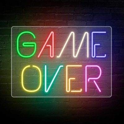 Placa em néon colorida com texto GAME OVER numa parede de tijolos