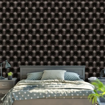 Quarto com cama cinzenta, roupa de cama cinza claro com pontos brancos, mesas de cabeceira com candeeiros e parede acolchoada preta