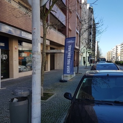 Rua com carros estacionados e loja Casa das Toalhas com faixa azul