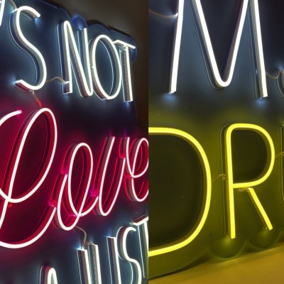 Letreiros em néon coloridos com texto em inglês sobre fundo escuro.