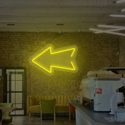 Interior de café com decoração em parede de tijolos e seta amarela em neon
