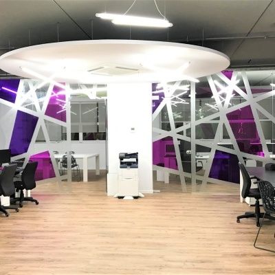 Escritório moderno com mesas de trabalho, cadeiras pretas e decoração geométrica roxa