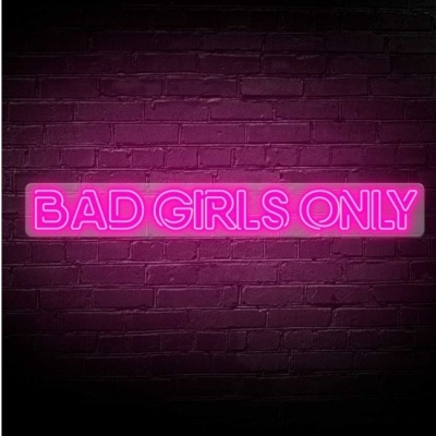 Letreiro de néon rosa com a frase BAD GIRLS ONLY numa parede de tijolos escuros