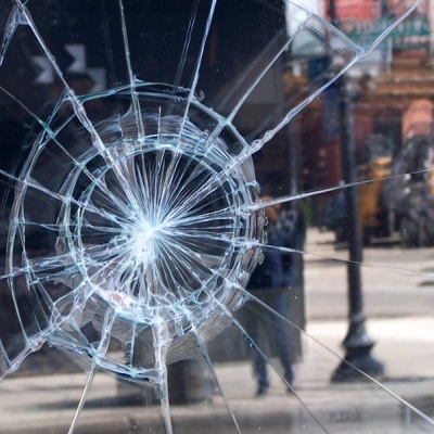 Vidro partido com padrão de teia de aranha e reflexos de cidade