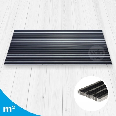 Tapete retangular preto com textura canelada e bordas prateadas sobre chão de madeira clara