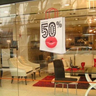 Vitrine com mobília moderna e saco de papel com texto '50%' e lábios vermelhos