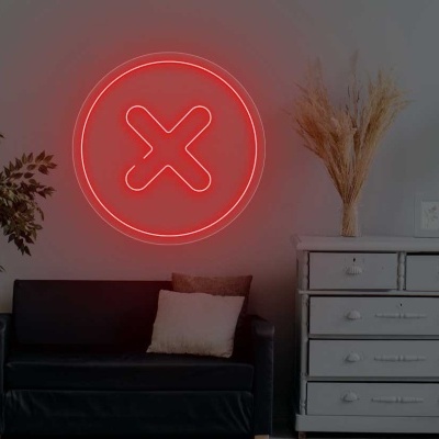 Sala com sofá preto, planta, cómoda cinza e símbolo vermelho em forma de X na parede