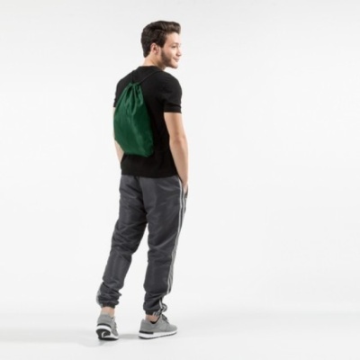 Homem com t-shirt preta, calças cinzentas e mochila de cordão verde