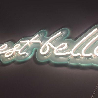 Letreiro luminoso branco com a frase 'love est belle'