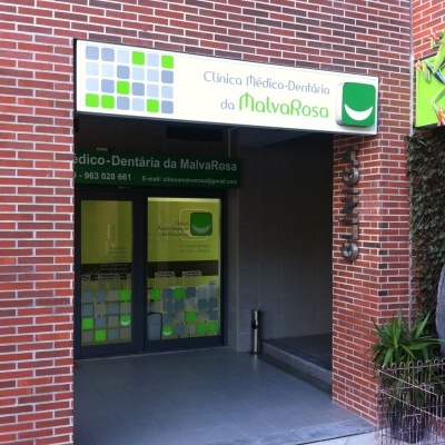 Entrada de clínica médico-dentária com placa e porta de vidro