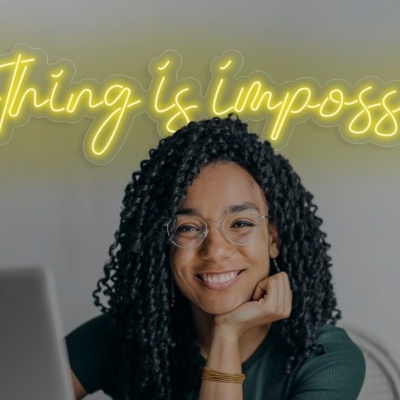 Mulher sorridente com óculos e letreiro em néon atrás