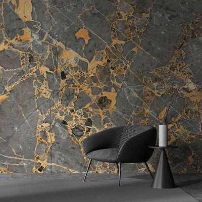 Poltrona preta com mesa lateral preta e vela junto a parede de mármore cinza e dourado