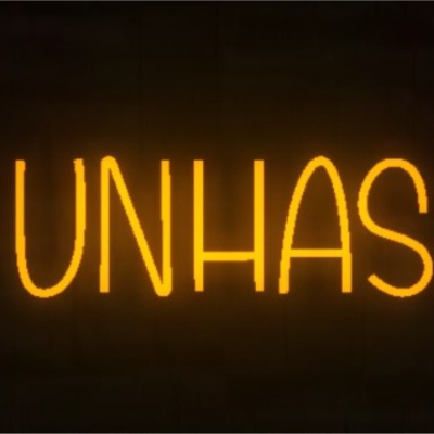 Letreiro de néon laranja com a palavra 'UNHAS' em parede de tijolos escura