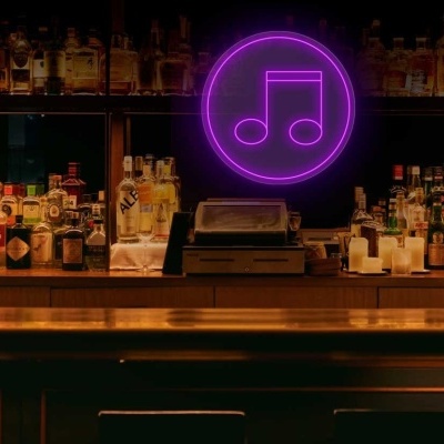 bar com balcão de madeira e prateleiras com garrafas, letreiro de néon roxo em forma de nota musical