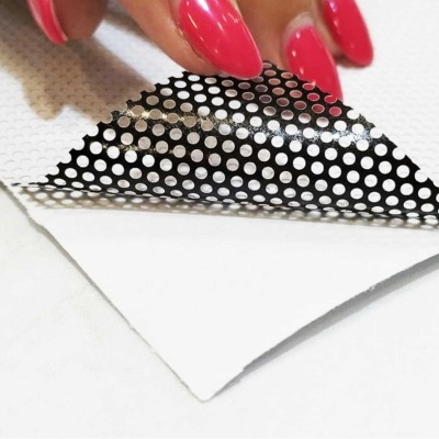 Mão aplicando folha autoadesiva preta com pontos brancos