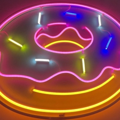 Sinal de néon de donut com cobertura rosa e granulados coloridos