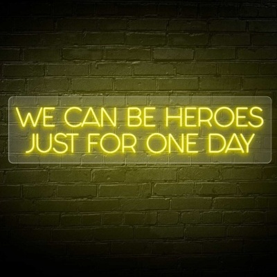 Letreiro de néon amarelo com texto em parede de tijolos verde escuro