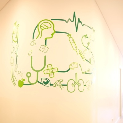 ilustração médica verde na parede branca de corredor iluminado com cadeiras ao fundo