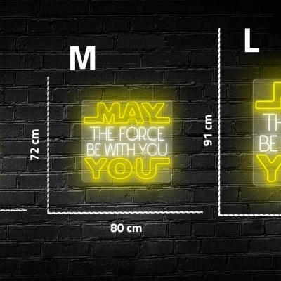 Três letreiros luminosos amarelos com texto 'MAY THE FORCE BE WITH YOU' em tamanhos S, M e L contra parede de tijolos pretos