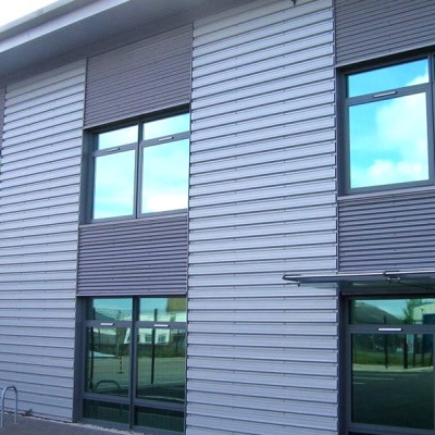 Fachada de edifício comercial moderno com painéis metálicos e janelas grandes