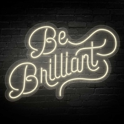 Letreiro de néon branco com as palavras Be Brilliant numa parede de tijolos escura