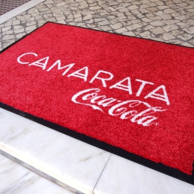 tapete vermelho com borda preta e texto branco CAMARATA Coca-Cola
