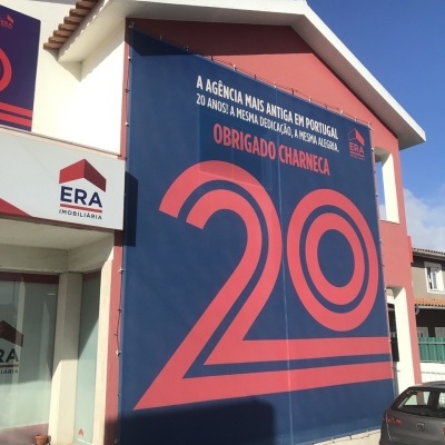 Cartaz azul e vermelho na parede exterior de uma imobiliária ERA