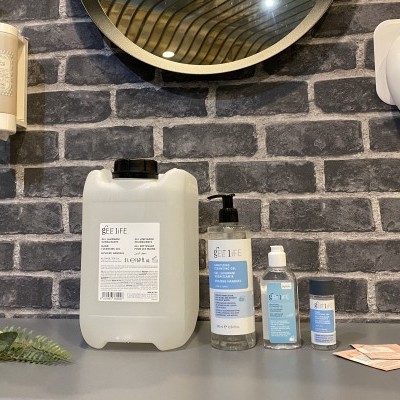 Produtos de higiene SEE LIFE em embalagens diversas sobre mesa cinzenta, parede tijolo escuro ao fundo