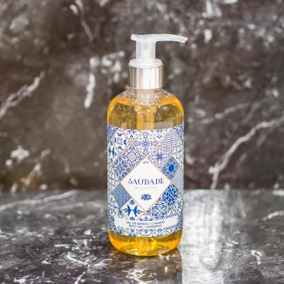 Frasco de gel de banho amarelo com rótulo azul e branco em mesa de mármore escuro