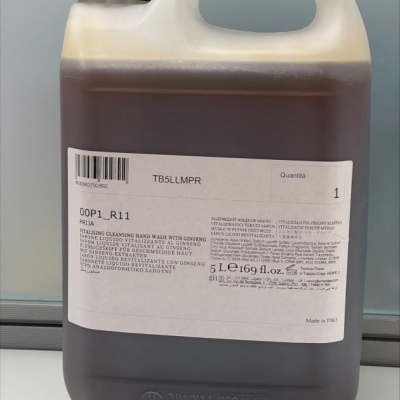 Recipiente plástico translúcido com líquido castanho escuro e etiqueta branca