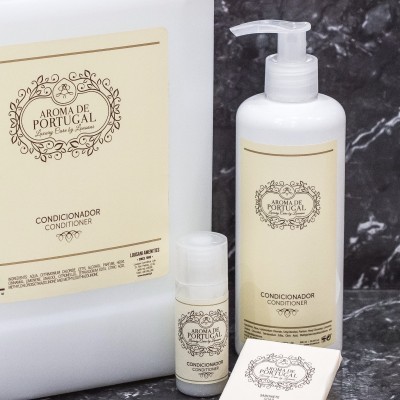 Conjunto de condicionadores Aroma de Portugal em embalagens brancas e rótulos bege sobre mármore.