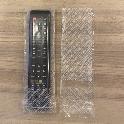 Comando remoto na embalagem de plástico sobre mesa de madeira clara