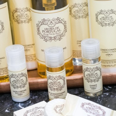 Produtos de hotelaria Aroma de Portugal em frascos pequenos creme e dourado em superfície escura