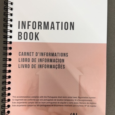 Livro de informações branco e rosa com texto multilíngue e espiral preta