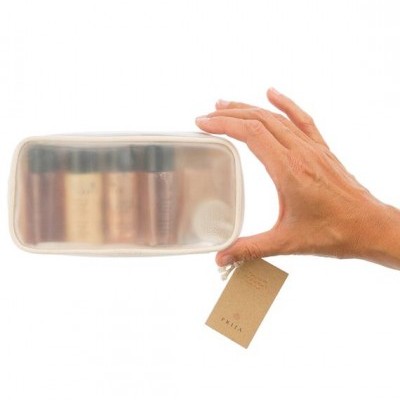 Necessaire semitransparente branca com pequenos frascos e etiqueta ILALIA segurada por mão