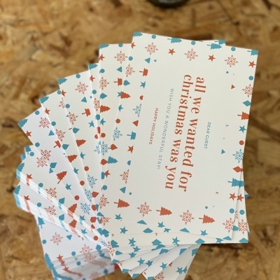 Cartões de Natal brancos com texto e padrão colorido sobre superfície de madeira