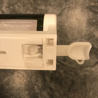 Dispositivo plástico branco com alavanca e cartucho preto com texto em fundo cinza