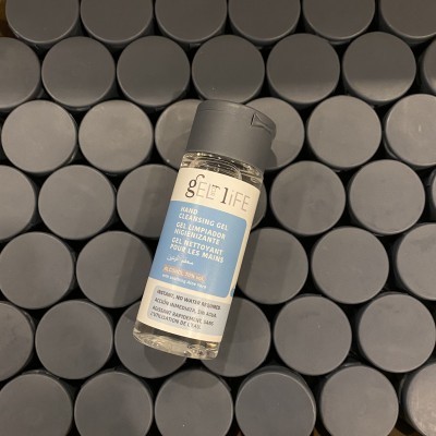 Frasco pequeno de gel desinfetante para mãos com tampa preta sobre tampas pretas circulares