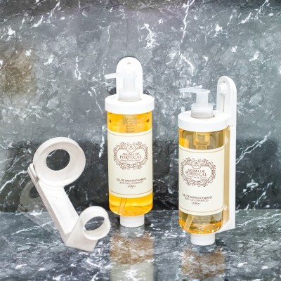 Duas garrafas de gel de banho espumoso com suporte branco montadas na parede sobre bancada de mármore cinza