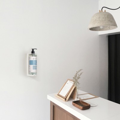 Dispenser de sabonete, balcão branco e luminária pendente sobre balcão em ambiente minimalista