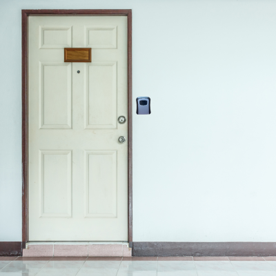 Porta de madeira branca com moldura castanha e dispositivo eletrônico preto na parede