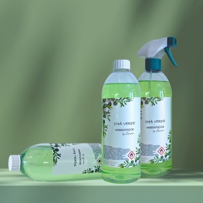 Três frascos de ambientador de chá verde com rótulos brancos e detalhes verdes num fundo verde claro