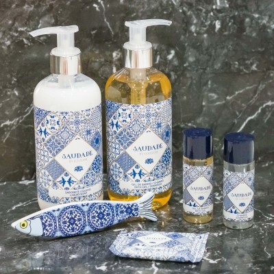 Produtos de higiene pessoal com padrão azul e branco chamados SAUDADE sobre mármore escuro