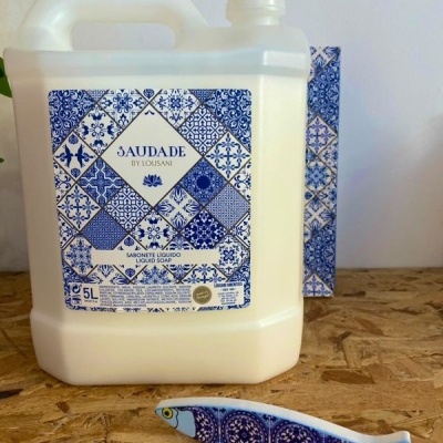 Frasco de sabonete líquido 3AUDADE BY LOUSANI com padrões de azulejos azuis e brancos, peixe decorativo azul e branco.