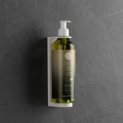 Frasco verde de cosmético com doseador numa parede cinzenta