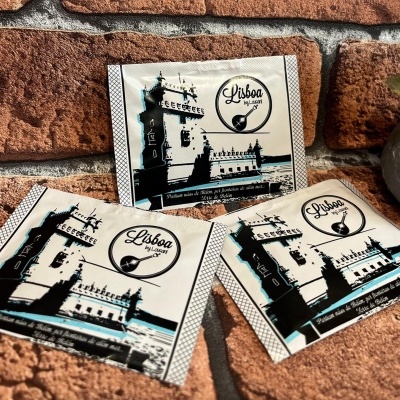 Pacotes com ilustrações da Torre de Belém e logótipo Lisboa by Louson sobre fundo de tijolo