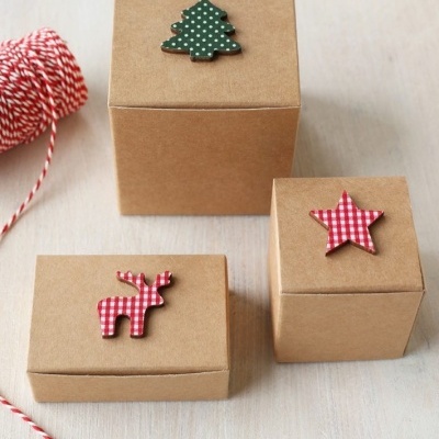 Caixas de presente de cartão castanho com decorações de madeira natalinas no topo