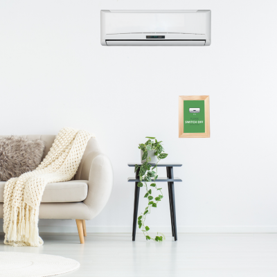 Ar condicionado branco na parede acima de sofá cinza claro com manta e mesa preta com planta